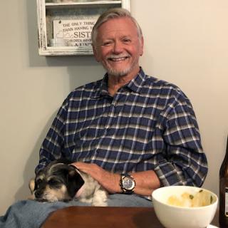 A cheerful man enjoying a moment with his dog, sharing some food.