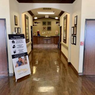 A clean and polished hallway in a building with framed decorations and informational signage.