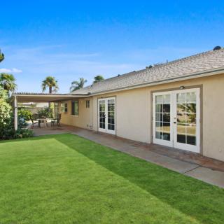 A cozy backyard featuring a well-maintained lawn and a covered patio area, perfect for outdoor relaxation.