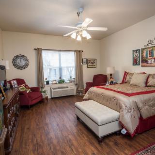 A cozy bedroom with a bed, comfortable chairs, and wooden flooring.