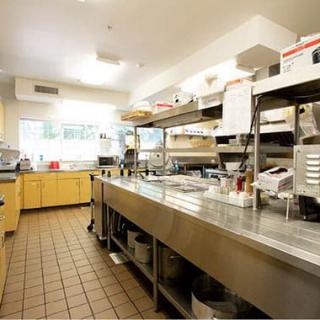 A spacious and well-organized commercial kitchen with stainless steel countertops and cooking equipment.