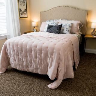 A cozy bedroom with a neatly made bed, side lamps, and neutral decor.