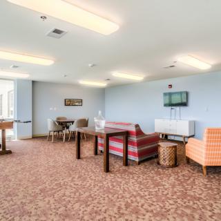 A spacious lounge area featuring various seating options, including sofas and chairs, with tables and carpeted flooring.