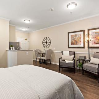 A cozy hotel room with a bed, chairs, and decorative artwork.