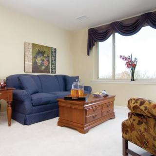 A cozy living room with a blue sofa, wooden coffee table, and artwork on the wall.