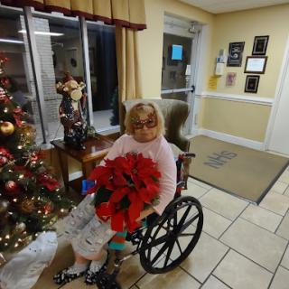 An elderly person holding festive poinsettias, surrounded by Christmas decorations in a warm, welcoming environment.
