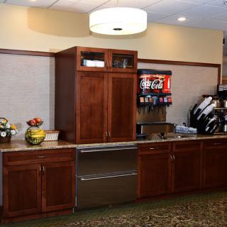 A kitchen area featuring wooden cabinetry and a beverage dispenser.
