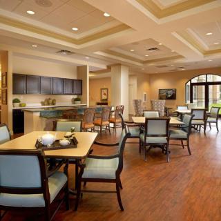 A modern dining area with tables and chairs, featuring wooden flooring and bright lighting.