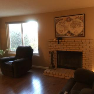 A cozy living room with a fireplace, armchair, and map artwork on the wall.