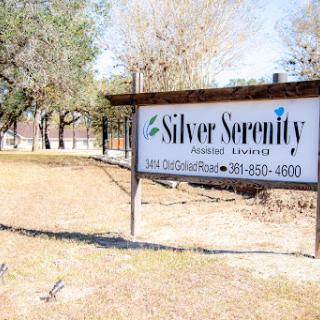 A sign displaying the name and contact information for Silver Serenity, set in a grassy outdoor area.