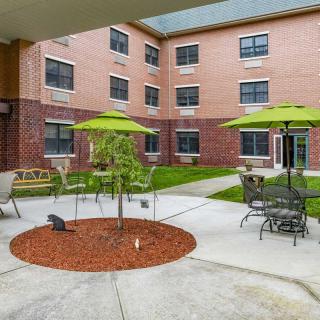 A well-maintained courtyard featuring outdoor seating and umbrellas in an apartment complex.