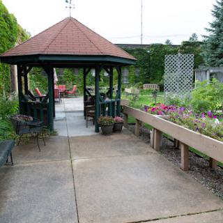 A serene garden featuring a gazebo, benches, and vibrant flowers along the pathway.