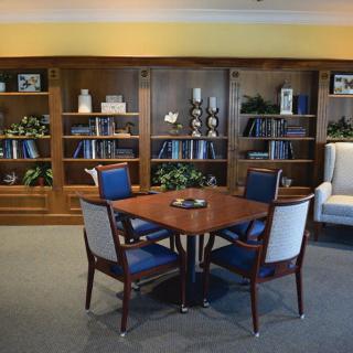 A cozy library space with a wooden table and chairs surrounded by bookshelves.