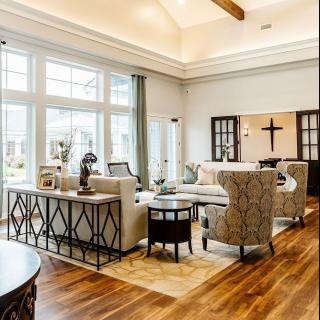 A spacious living room with large windows allowing natural light to fill the space, featuring elegant furniture and wooden flooring.