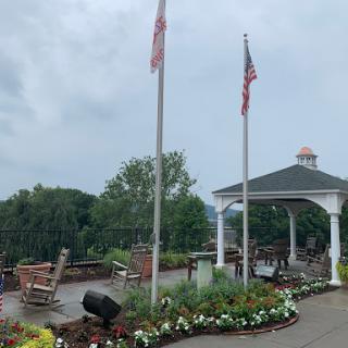 A peaceful outdoor space featuring flags and well-maintained gardens near a gazebo.