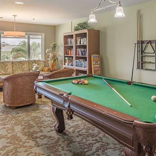 A cozy game room featuring a billiard table, comfortable seating, and a bookshelf.