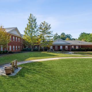 A sunny day at a courtyard with green lawns, benches, and surrounding buildings.