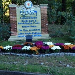 A sign for a healthcare and rehabilitation center surrounded by colorful flowers.