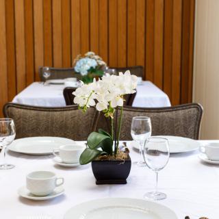 An elegantly set dining table featuring a centerpiece with white orchids.