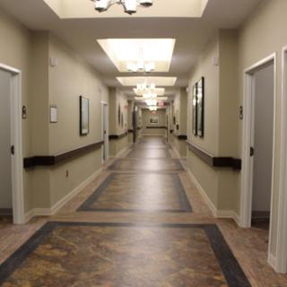 A well-lit hallway featuring several doors and framed artworks along the walls.