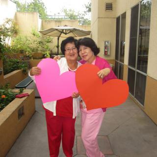 Two people holding large colorful hearts, celebrating outdoors.