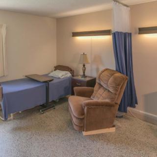 A hospital room with a bed and recliner, separated by a curtain.