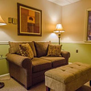 A cozy living room with a comfortable sofa, warm lighting from lamps, and decorative wall art.