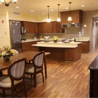 A modern kitchen and dining area with a central island, wood flooring, and elegant lighting.