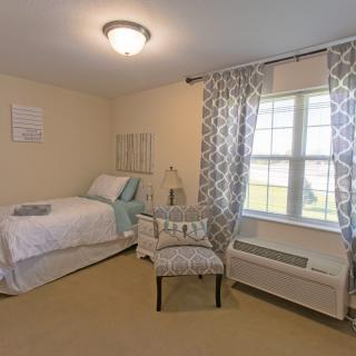 A cozy, well-lit bedroom with a single bed and patterned curtains.
