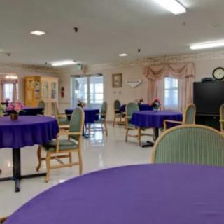 An empty dining area with tables covered in purple tablecloths.