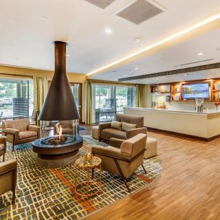 A modern lounge area featuring a central fireplace, comfortable seating, and wood flooring.