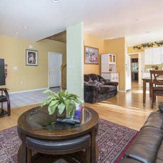 A cozy living room with a sofa, wooden tables, a rug, and decorative plants.
