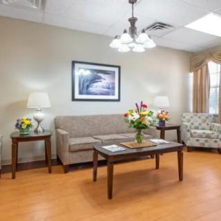 A cozy living room with a sofa, armchair, and a coffee table adorned with fresh flowers.