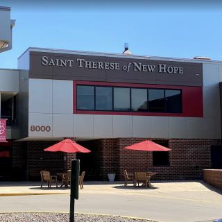 The exterior of Saint Therese of New Hope with outdoor seating and umbrellas.