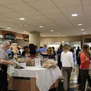A busy cafeteria with people gathering around food counters.