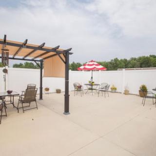 A spacious outdoor patio area with a pergola and shaded seating, perfect for leisurely moments.