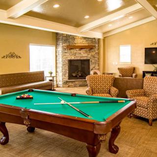 A cozy living room with a billiards table and a fireplace.