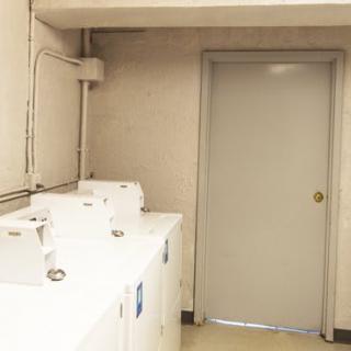 A small laundry room with multiple washing machines lined up against the wall.