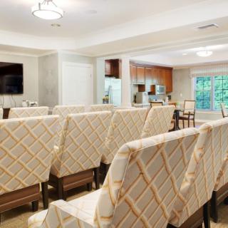 A well-lit conference room with several rows of patterned chairs facing a television.