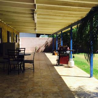 A shaded patio area with outdoor furniture and a view of the garden.