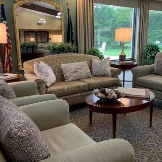 A cozy living room with sofas, armchairs, and a coffee table in front of large windows.
