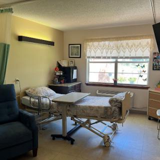 A serene hospital room equipped for patient care, featuring a hospital bed and a cozy chair by the window.
