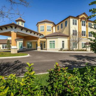 A modern residential building with a covered entrance and well-maintained landscaping on a sunny day.