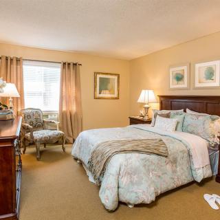 A cozy bedroom with classic furnishings, featuring a comfortable bed and elegant decor.