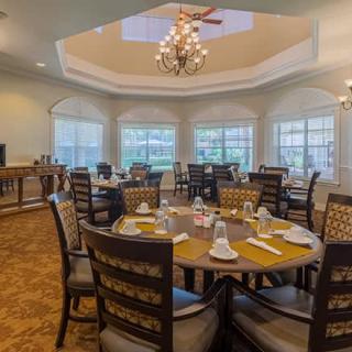 An elegant dining room with tables set and a chandelier overhead.