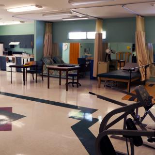 A spacious rehabilitation center equipped with various exercise and therapy apparatus in a calm, inviting environment.
