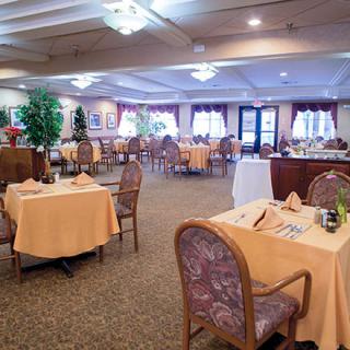 A spacious and elegantly decorated dining area with neatly arranged tables and chairs, featuring warm lighting and a cozy atmosphere.
