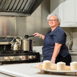 A woman is cooking in a modern kitchen, showing her culinary skills.