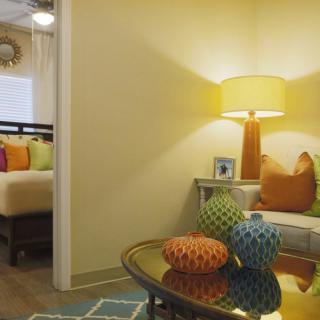 A cozy living space with a vibrant, modern decor featuring colorful pillows and a warm lamp.