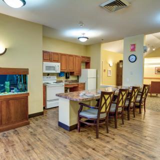 A cozy kitchen and dining area with an aquarium, featuring a wooden floor and appliances.